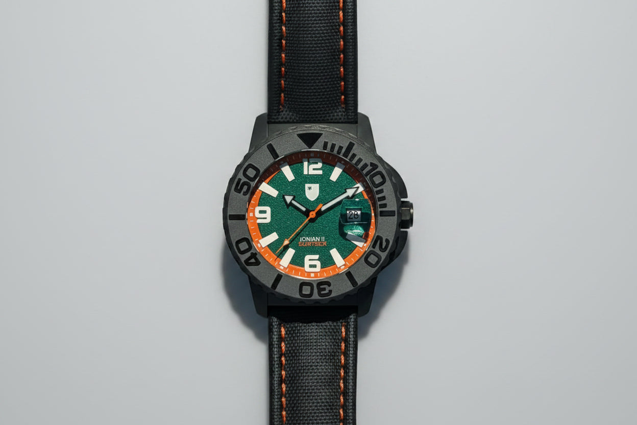 Watch with a green face and black strap on a pebbled surface