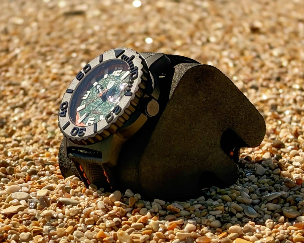 Watch with a detailed face and leather strap on a pebbly surface