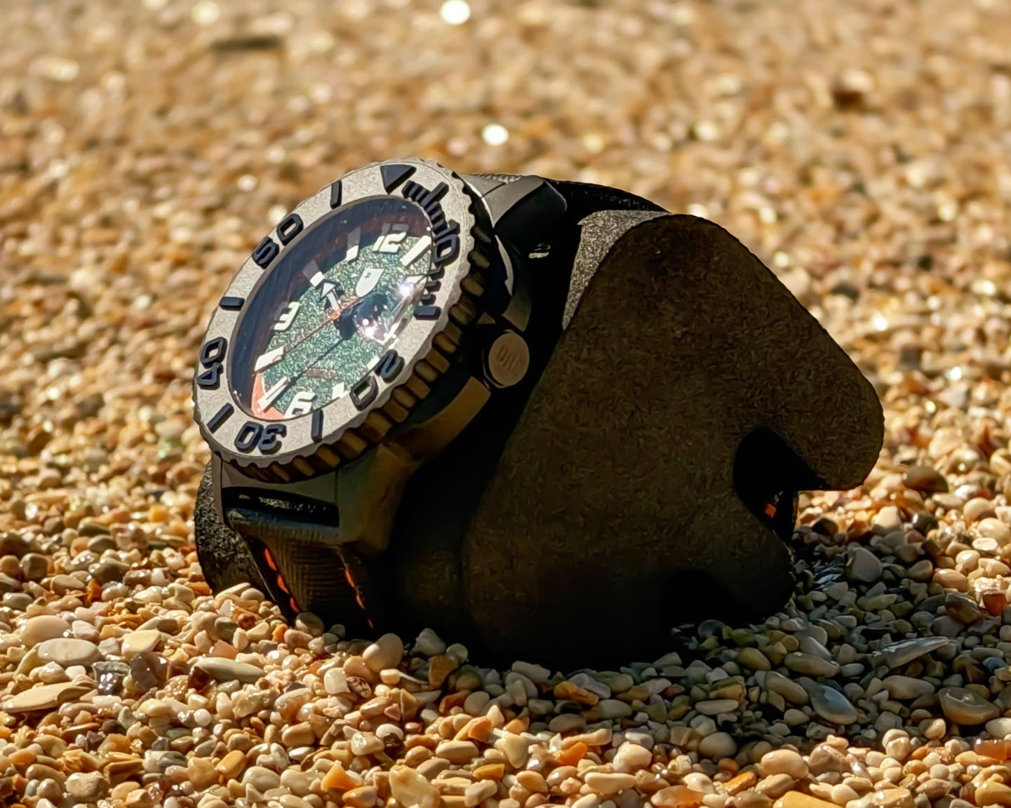 Watch with a detailed face and leather strap on a pebbly surface