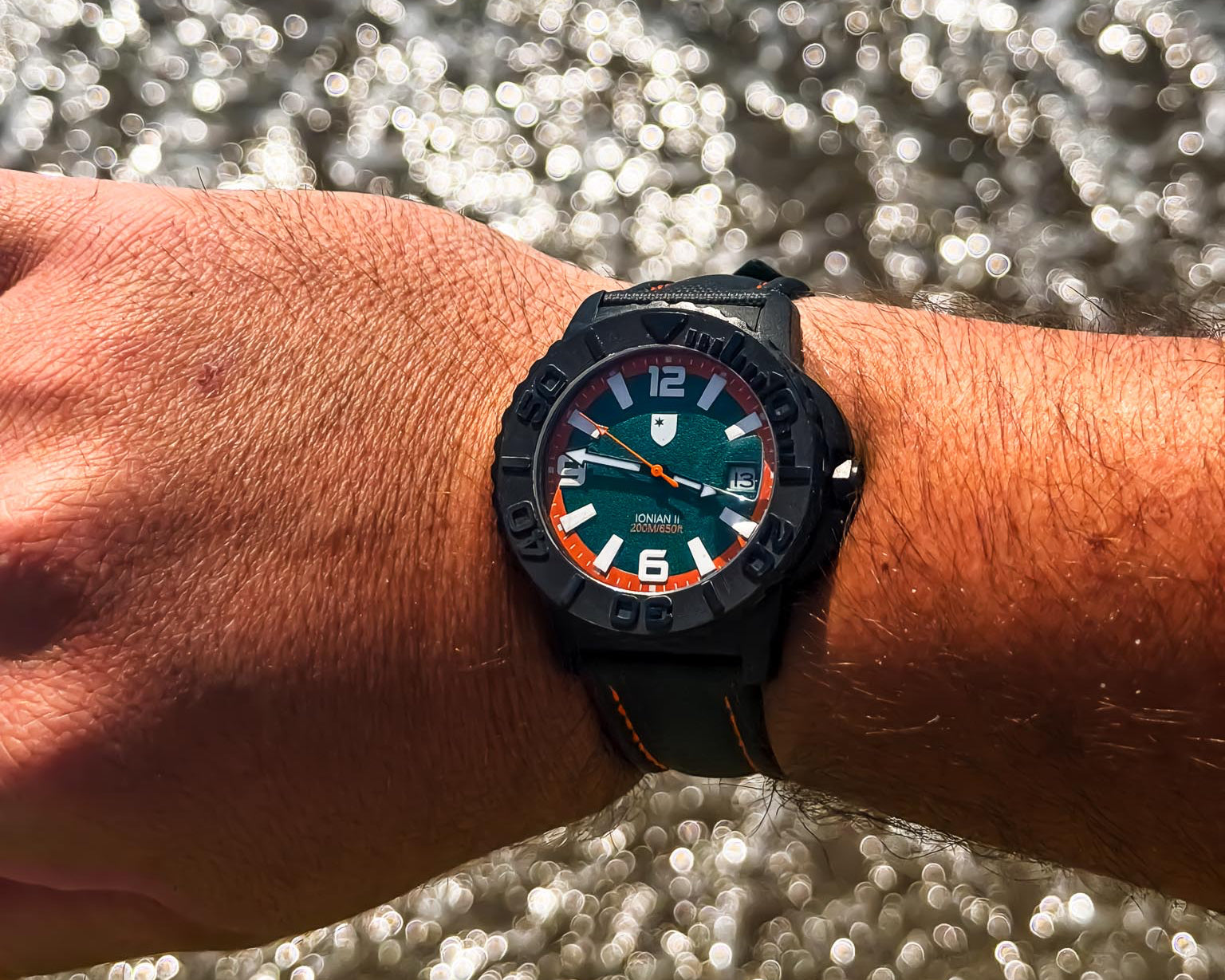 Wrist wearing a watch with a blurred water background