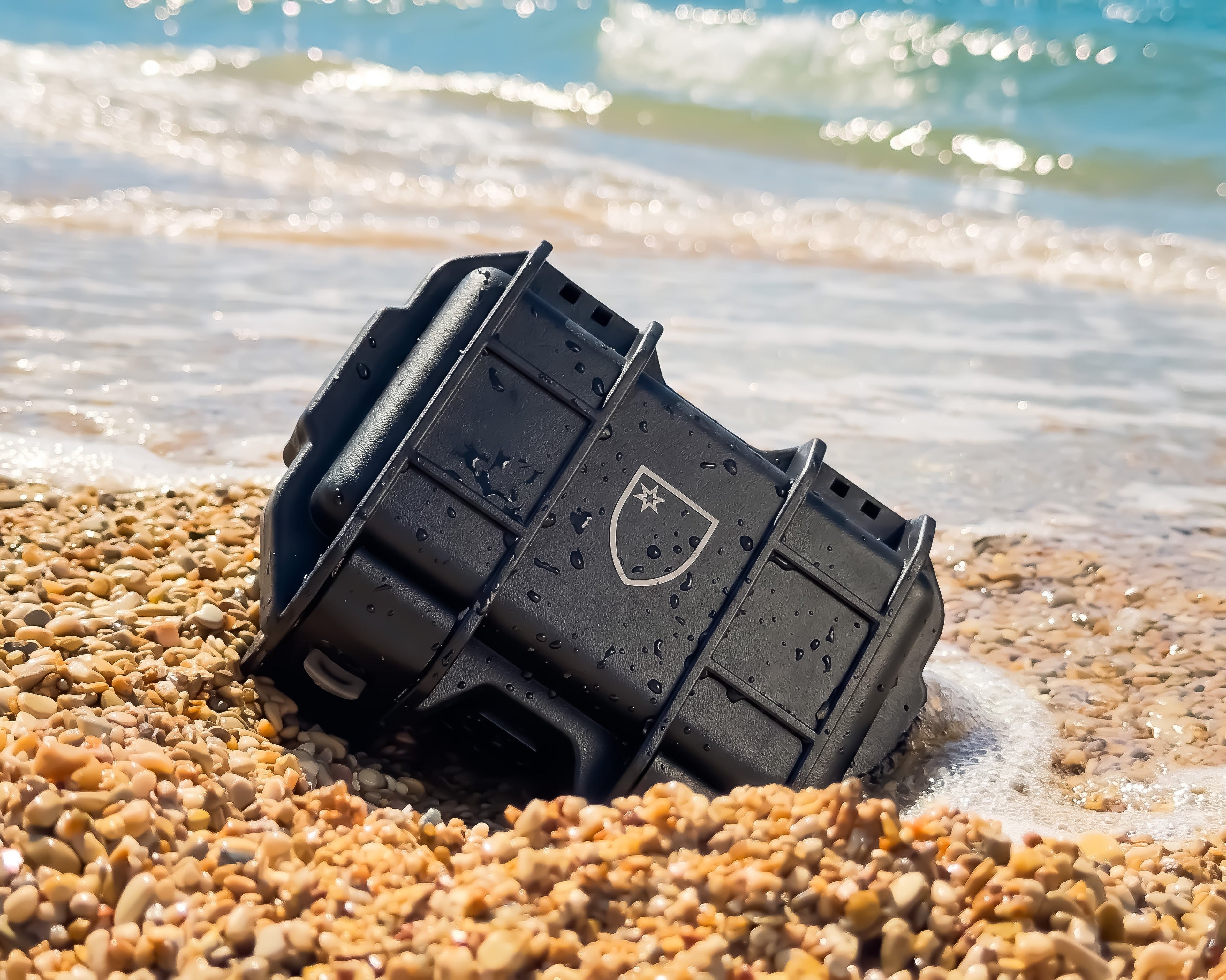 Black protective case on a beach with water in the background